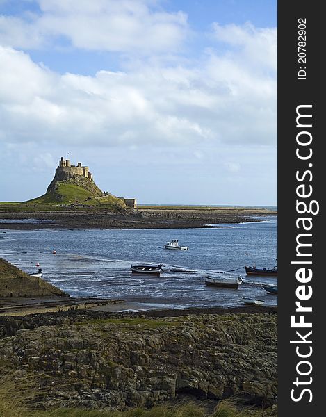 Lindisfarne castle nestling in background with fishermans boats in forground