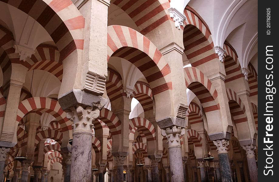 Red and white arches sit above numerous pillars in the famous Mezquita cathedral in Cordoba, Spain. Red and white arches sit above numerous pillars in the famous Mezquita cathedral in Cordoba, Spain.