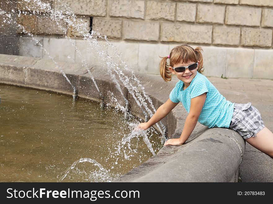 Little girl playing with water - the fountain