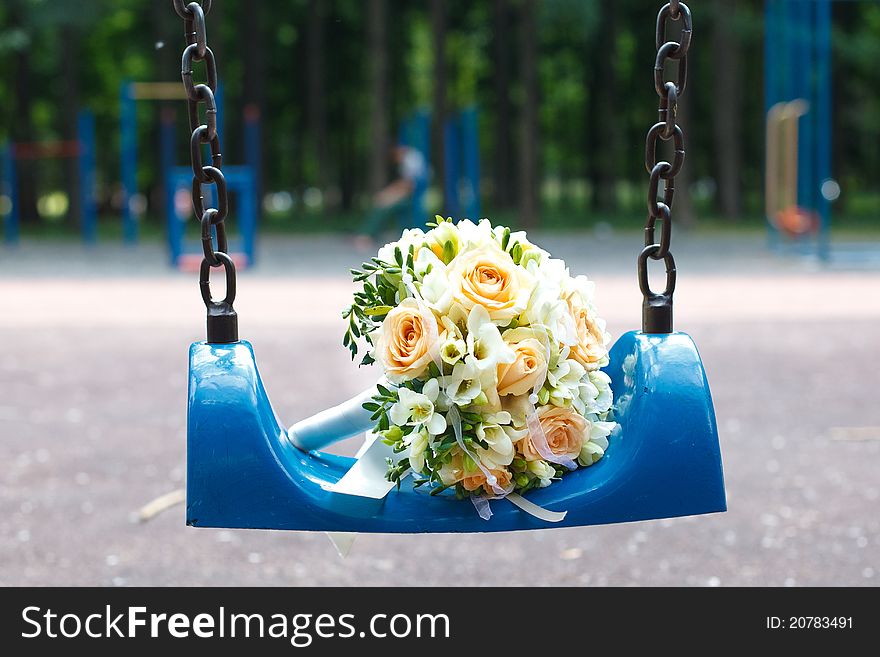 Wedding bouquet on blue swing in park