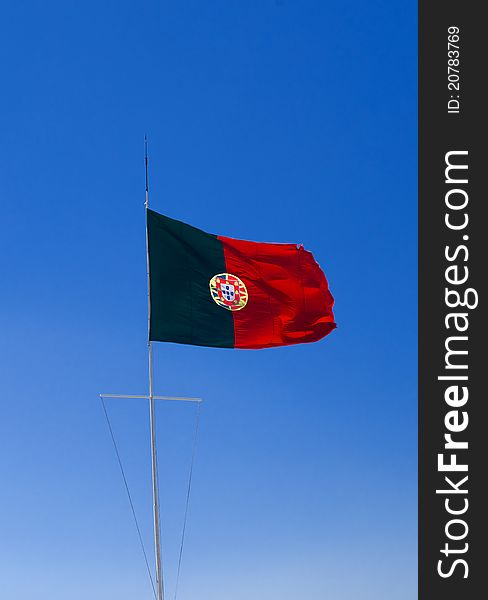 Portuguese flag against a vibrant blue sky.