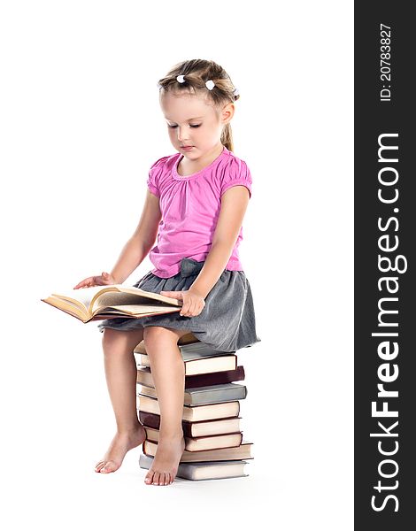 3 years old girl sitting on a cup of books and reading on white. 3 years old girl sitting on a cup of books and reading on white
