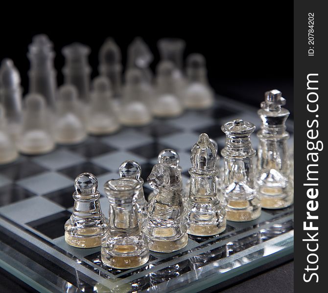 A checkmate situation on a glass chessboard against a black background. A checkmate situation on a glass chessboard against a black background