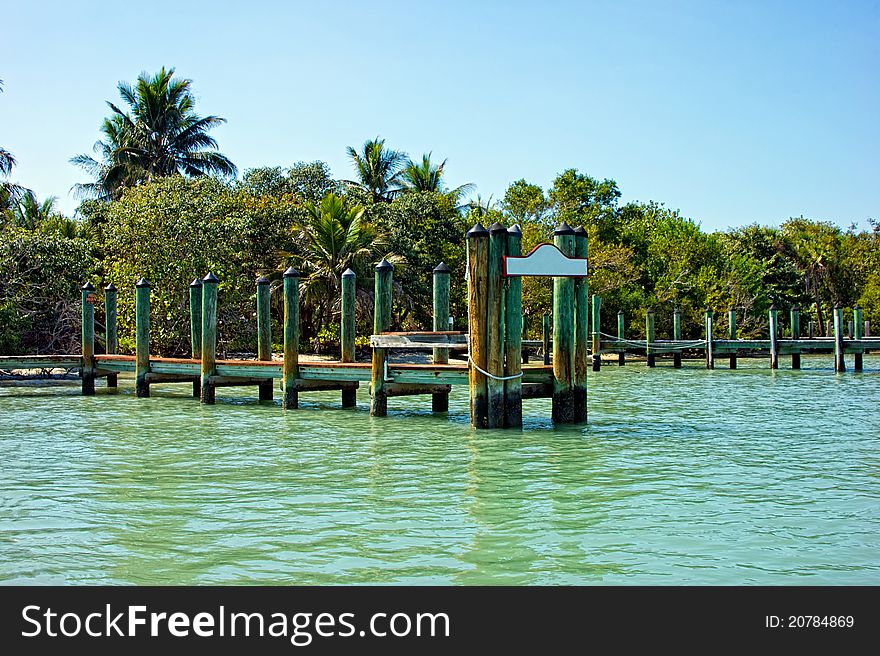 A blank sign on the end of a wooden rustic pier that leads to a tropical island in south west florida. A blank sign on the end of a wooden rustic pier that leads to a tropical island in south west florida