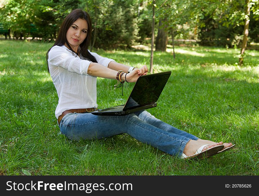 Beautiful woman with long hair wearing jeans stretched on the nature of the computer. Beautiful woman with long hair wearing jeans stretched on the nature of the computer