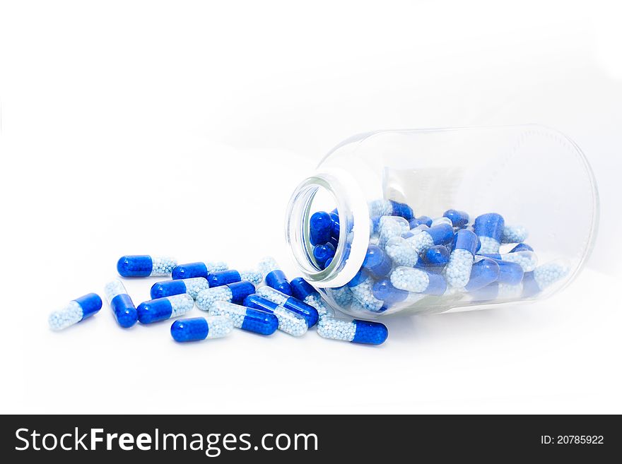 Pills spilling out of pill bottle over white