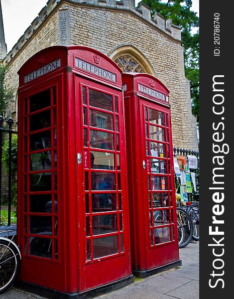 2 red phone box's stand in front of an old church in Cambridge UK.