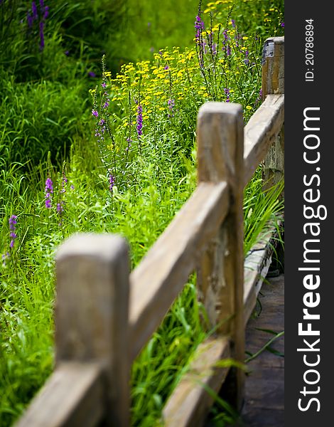 Wooden garden fence against green grass and flowers.