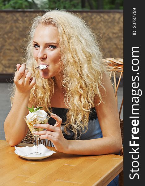 Outdoor portrait of young beautiful girl eating fruit dessert. Outdoor portrait of young beautiful girl eating fruit dessert