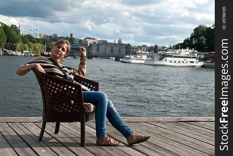 Beautiful girl sitting in a chair on the pier. Beautiful girl sitting in a chair on the pier