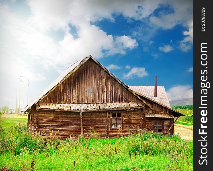 Vintage wooden house in the countryside over blue sky with artistic lights and shadows added