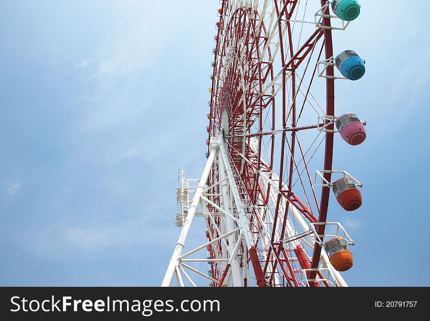 Low angle view of ferris wheel with colorful gondolas and blue sky background. Photo taken on: Aug 8, 2011 in Japan