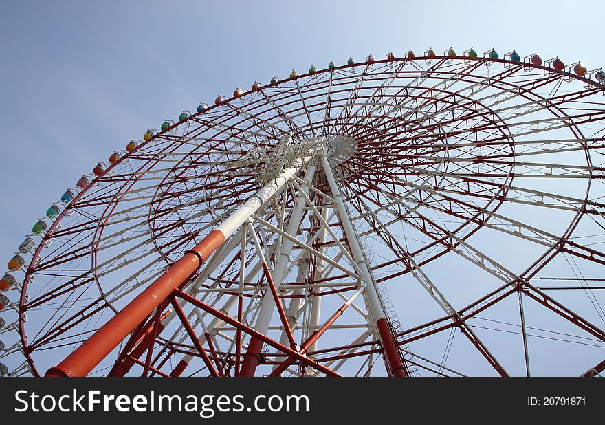 Low angle view of ferris wheel with colorful gondolas and blue sky background. Photo taken on: Aug 8, 2011 in Japan