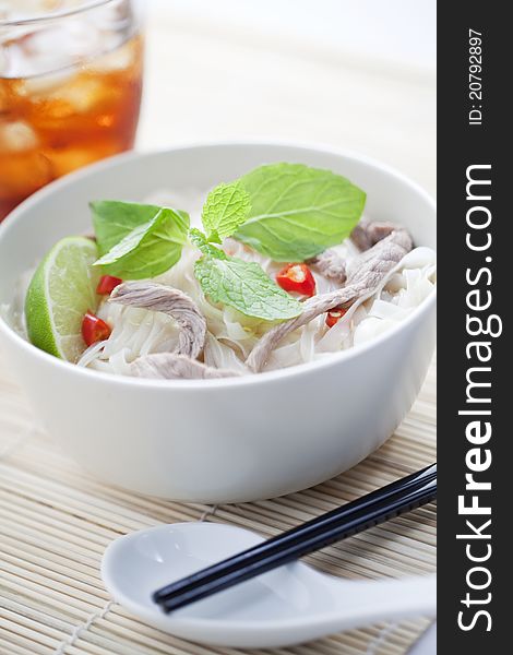 A bowl of beef noodles served with drink.