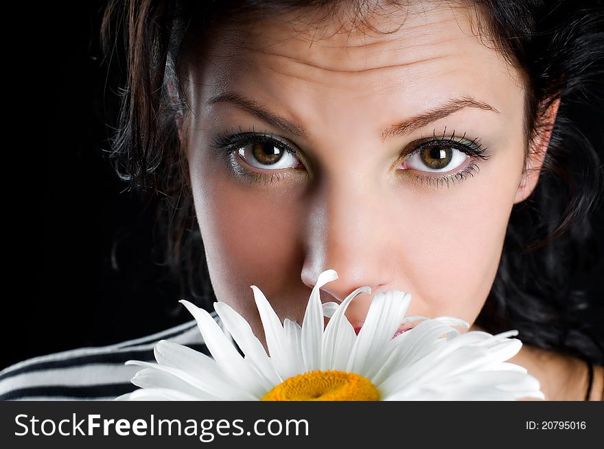 Beautiful young woman with chamomile in hand on black