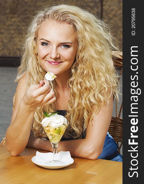 Outdoor portrait of young beautiful girl in the cafe eating fruit dessert
