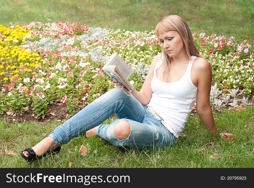 Girl sitting in the garden and reading a book