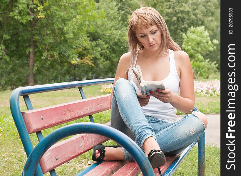 Girl on a park bench reading a book