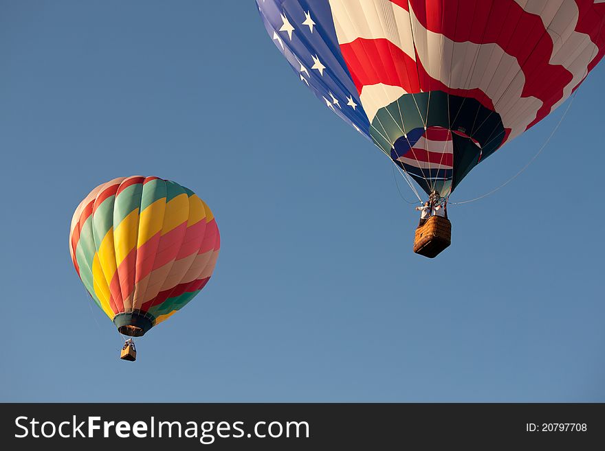 2 colorful hot air balloons flying away. 2 colorful hot air balloons flying away