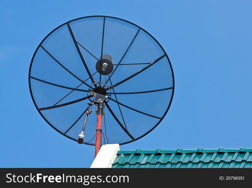 Satellite Dish on green roof tile against blue sky. Satellite Dish on green roof tile against blue sky