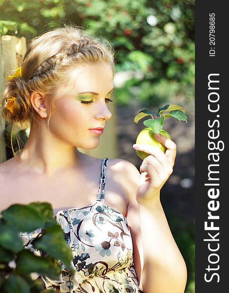 Young woman holding a green apple on a light background