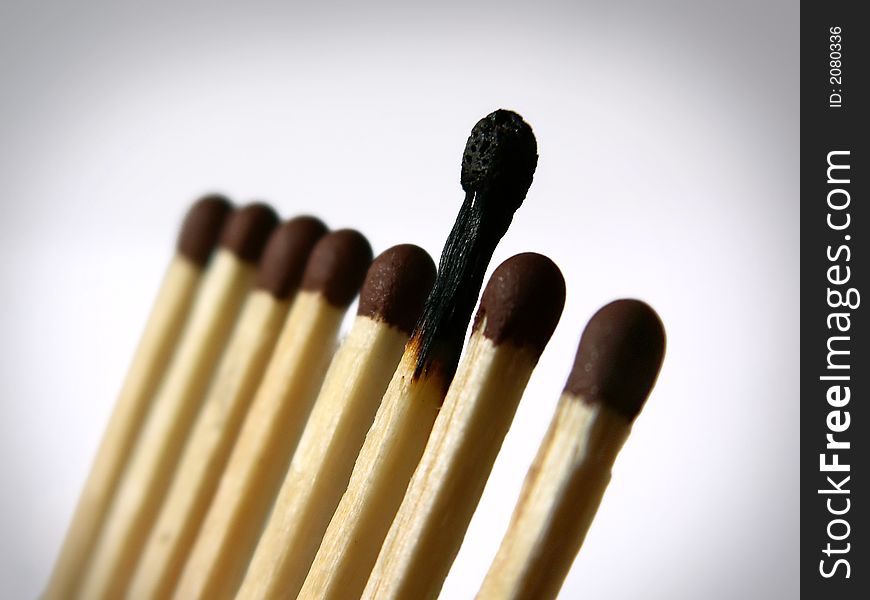 Close-up photo of several matches in a row with one burnt