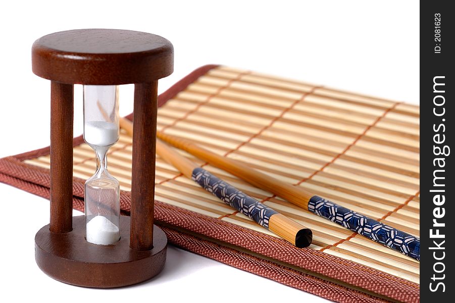 Composition of chopsticks, sand glass and bamboo table-cloth over white background. Composition of chopsticks, sand glass and bamboo table-cloth over white background