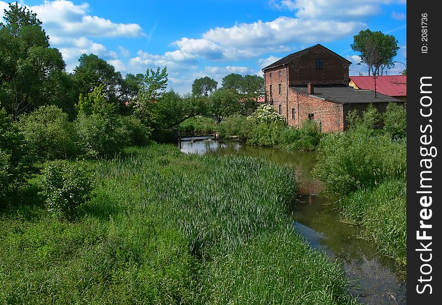 A water mill with green trees and grass around. A water mill with green trees and grass around