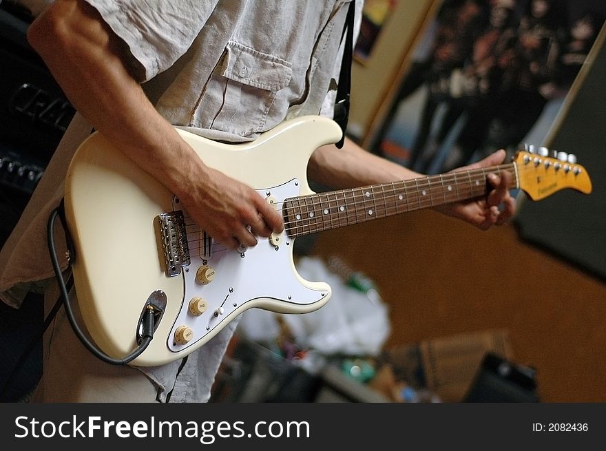 A man playing an a white, electric guitar. A man playing an a white, electric guitar.