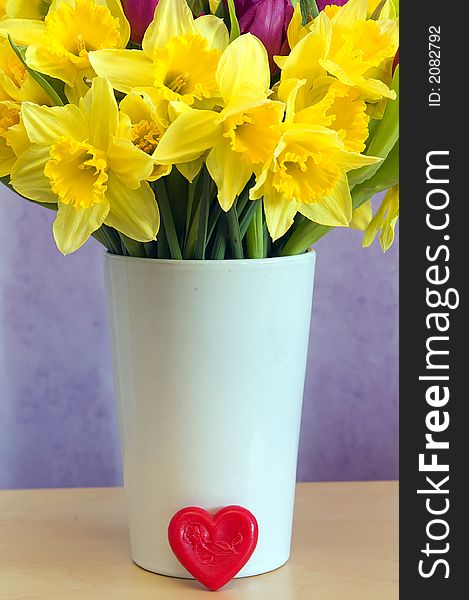 Brightly coloured spring flowers on a vase with a red heart. Brightly coloured spring flowers on a vase with a red heart