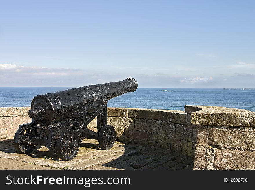 A historic cannon looking out over sea from the tower of a castle