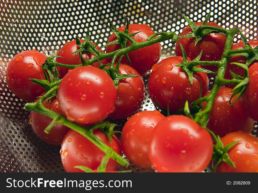 Freshly washed tomatoes in a stainless steel colander