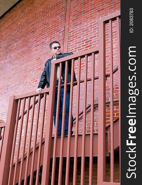 Man in a pensive mode standing on the steep stair case of a large circular red brick building. Man in a pensive mode standing on the steep stair case of a large circular red brick building.