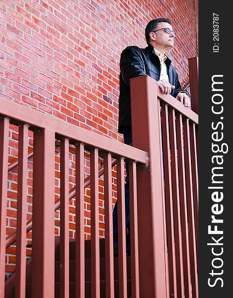 Man standing on the steep stair case of a large red brick building thoughtfully surveying his surroundings. Man standing on the steep stair case of a large red brick building thoughtfully surveying his surroundings.