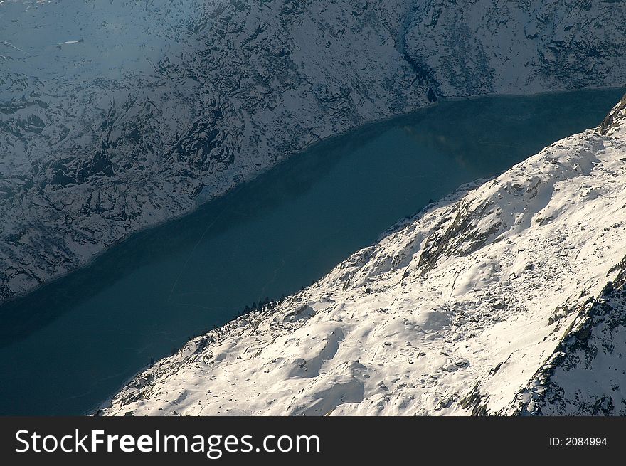 Dark Blue Lake Surrounded By Snowy Swiss Mountains