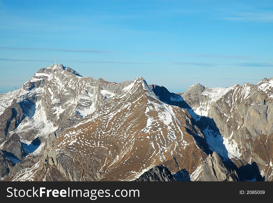 Swiss Alps (mountains) shot from small Airplane. Rocks with some snow. Blue sky background. Swiss Alps (mountains) shot from small Airplane. Rocks with some snow. Blue sky background.