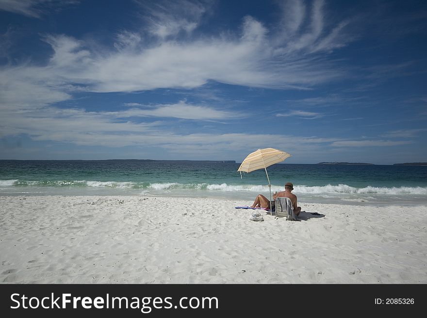 Couple sitting on a tropical beach under an umbrella. Couple sitting on a tropical beach under an umbrella