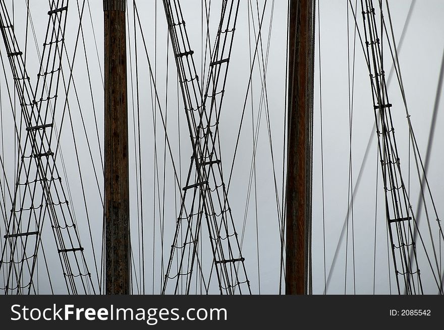 Two ship masts against a gray sky