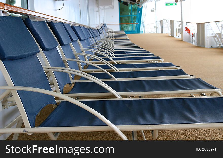 Blue lounge chairs lined up on deck of a ship. Blue lounge chairs lined up on deck of a ship
