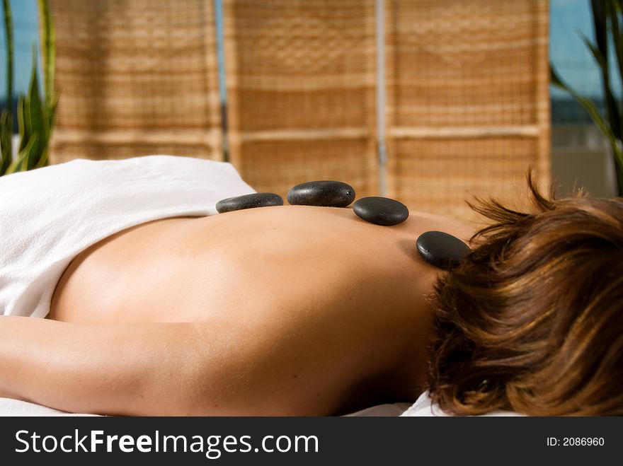 Woman in a day spa with hot stones on her back. Woman in a day spa with hot stones on her back