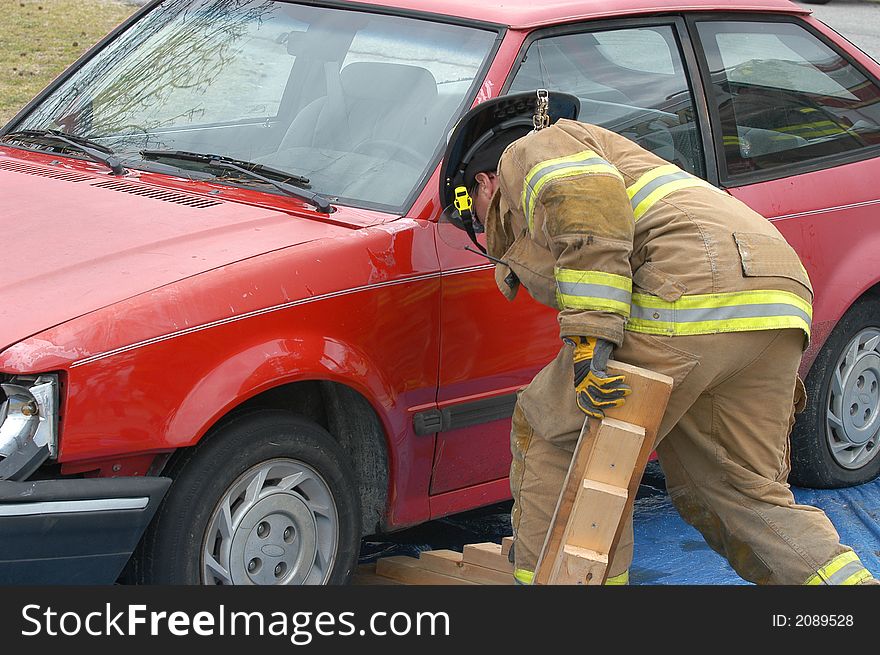 Fireman cutting into a wrecked car to remove the driver. Fireman cutting into a wrecked car to remove the driver.