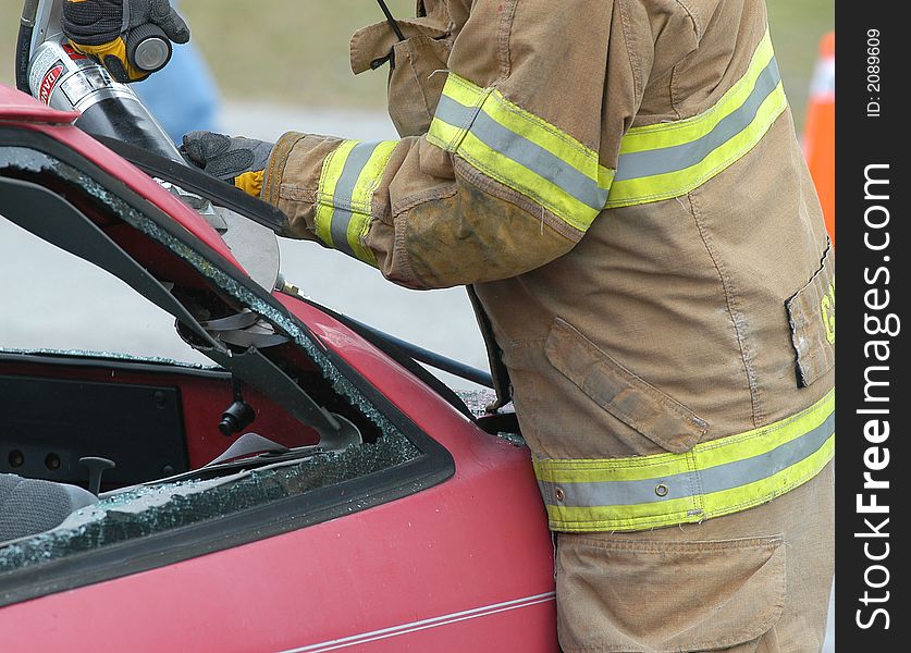 Fireman cutting into a wrecked car to remove the driver. Fireman cutting into a wrecked car to remove the driver.