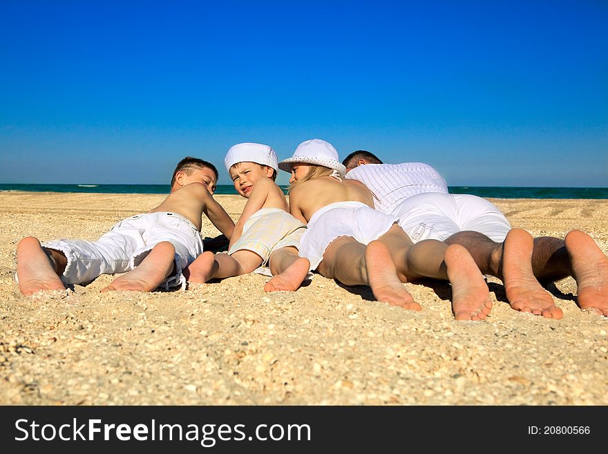 Photo of  family lying on sand on background of blue sky