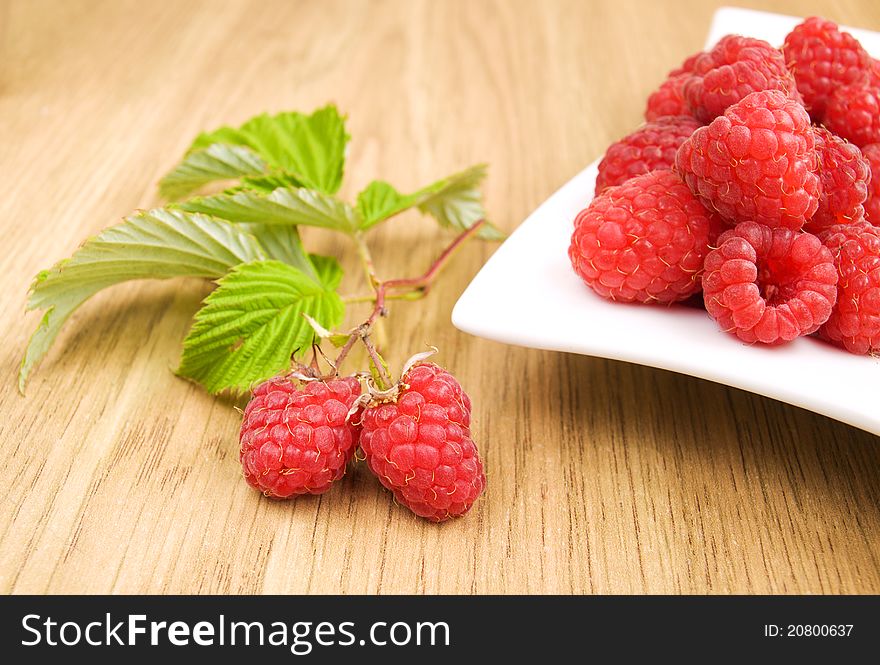 Plate with fresh raspberries on the table