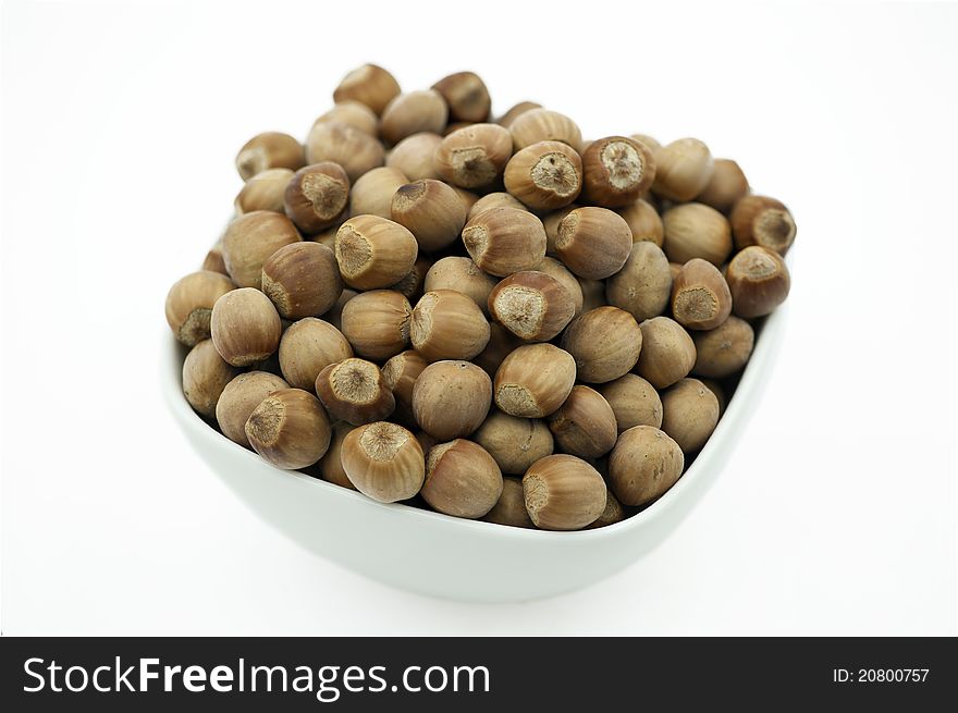 Hazelnuts in a white dish on the white background. Hazelnuts in a white dish on the white background