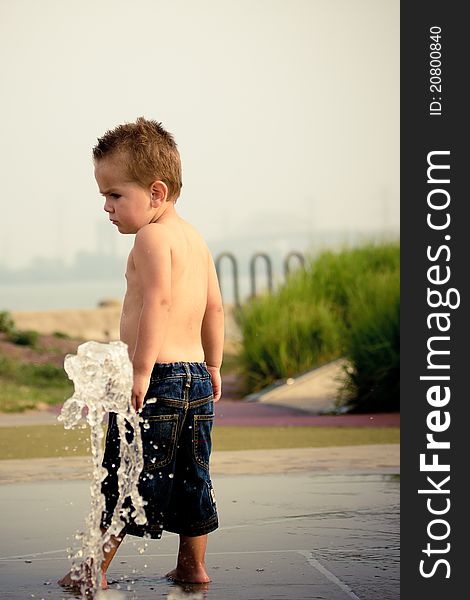 Two year old boy playing in water.