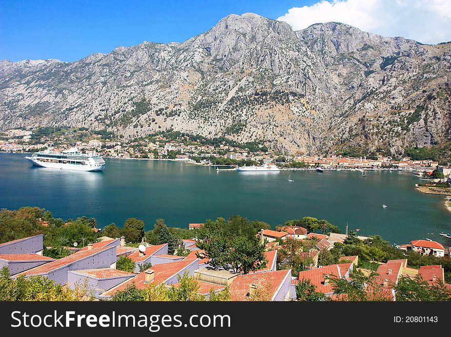 The view over the mighty mountains surrounding Boca bay or Kotor Bay of Montenegro and a cruise liner at anchor in the bay. The view over the mighty mountains surrounding Boca bay or Kotor Bay of Montenegro and a cruise liner at anchor in the bay