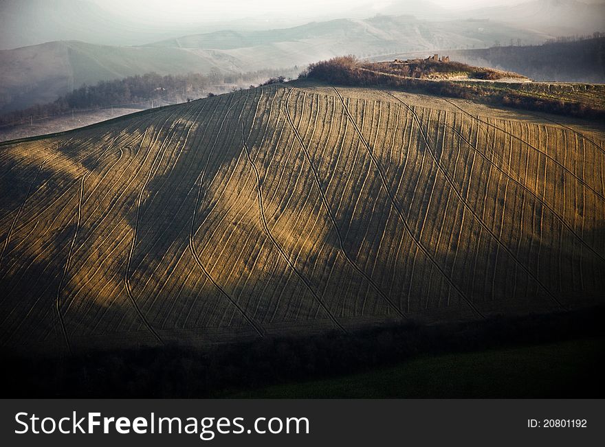 A recently plowed field on a hill, castle ruins in the distance