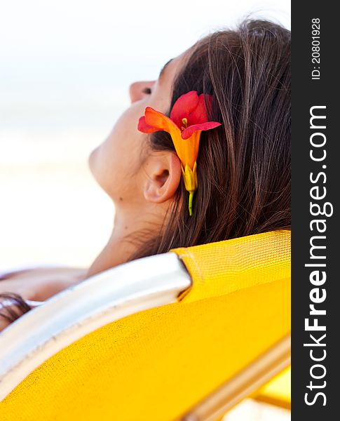 Beautiful young woman relaxing at the beach with a flower in her hair