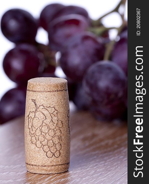 Wine cork and grape on wooden table